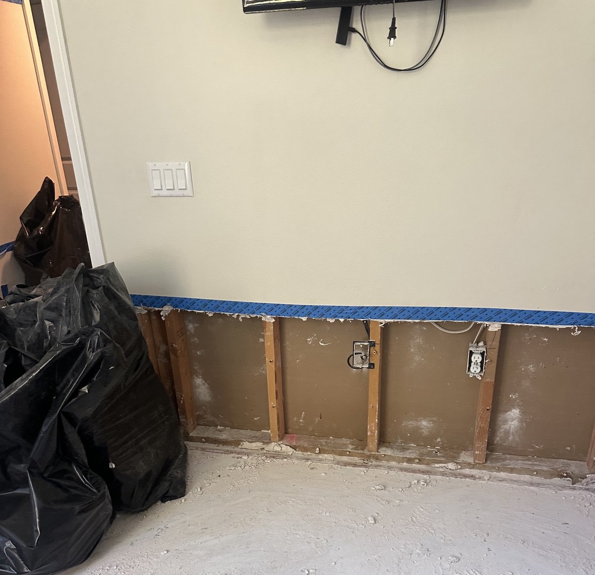Lower drywall removed to the studs along a wall during remediation – 77 Rapid Restore