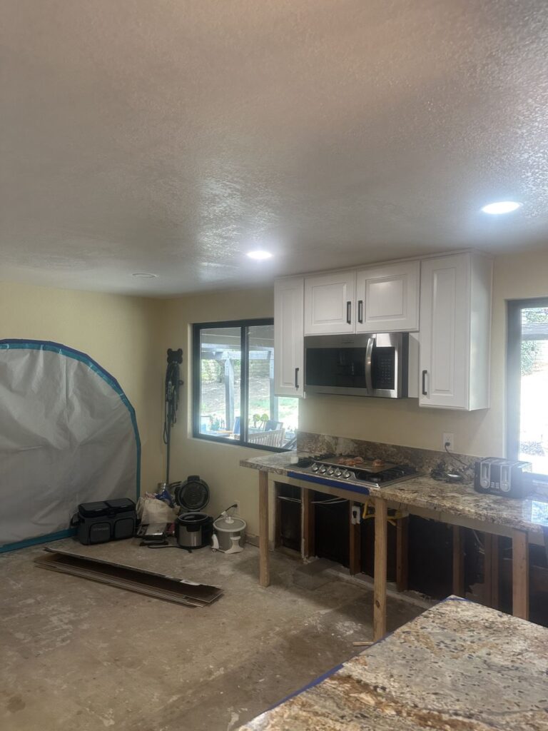 Kitchen during rebuild with lower cabinets removed and new upper cabinets installed – 77 Rapid Restore