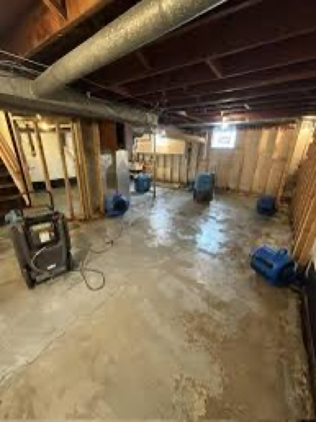 Air movers and a dehumidifier drying a lower-level concrete floor after water extraction – 77 Rapid Restore